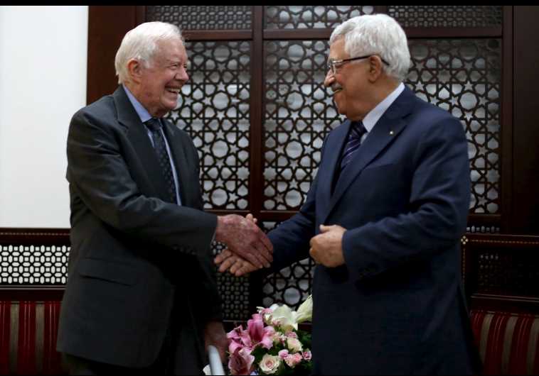 Palestinian President Mahmoud Abbas (R) shakes hands with former US president Jimmy Carter during their meeting in the West Bank city of Ramallah