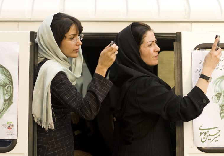 Iranian women take a picture of a presidential candidate with their mobile phones in Tehran , Iran
