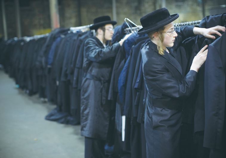 MEN SEARCH the cloak room for their jackets at a mass gathering of Satmar Hassidim in New York
