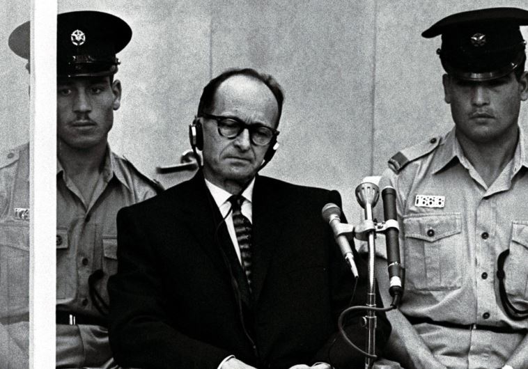 Israeli police flank Adolf Eichmann, the Nazi SS colonel who headed the Gestapo's Jewish Section and was responsible for millions of Jews' deaths in Nazi concentration camps, as he stands trial inside a bulletproof booth in a Jerusalem court