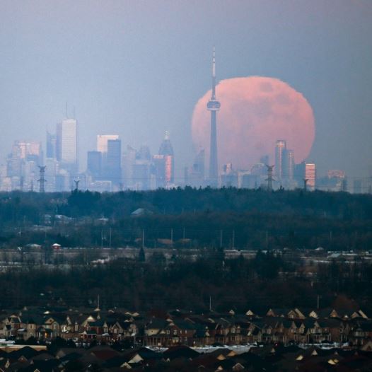 The moon rises over the Toronto city skyline as seen from Milton, Ontario
