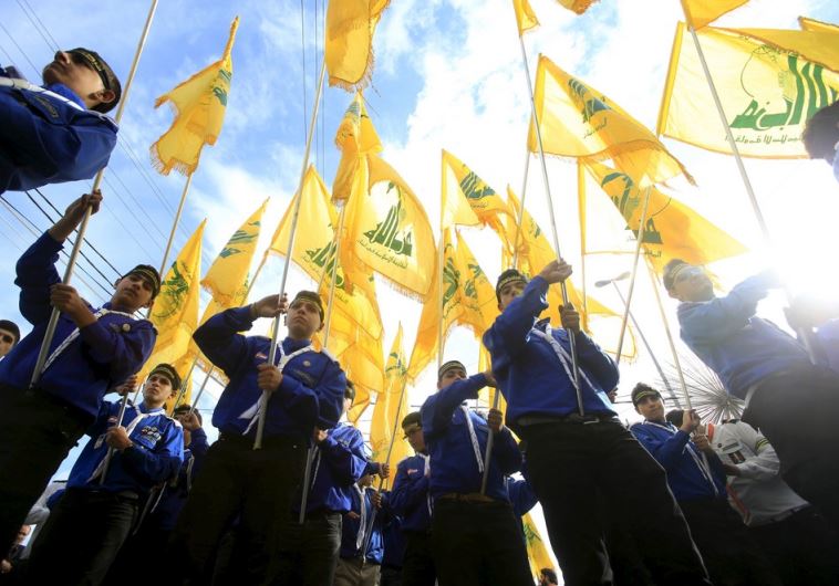 Lebanon's Hezbollah scouts carry their parties flag while marching at the funeral of three Hezbollah fighters who were killed in Syria