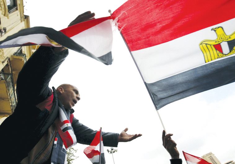 PRO-GOVERNMENT protesters chant slogans while holding the national flag during the fifth anniversary of the uprising that ended the 30-year reign of Hosni Mubarak, in Cairo in January