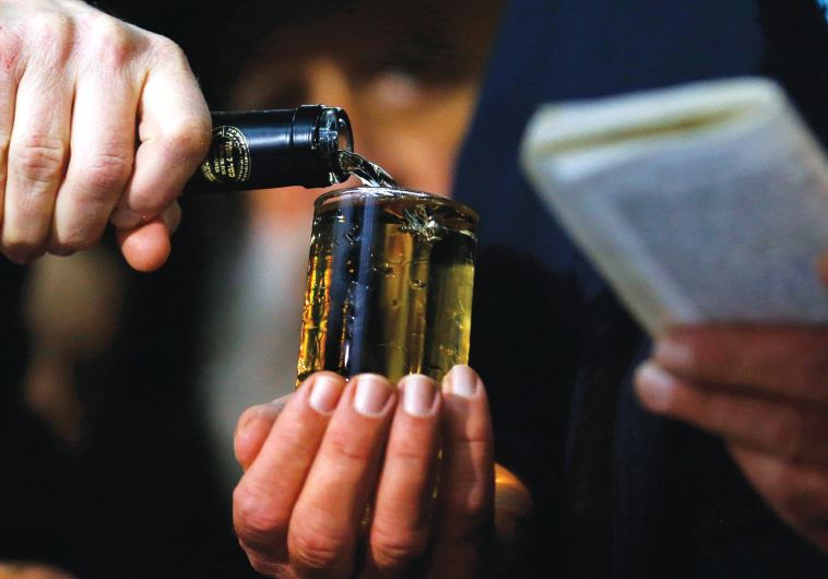 A CELEBRATORY GLASS OF WINE is poured before traditional blessings during an Orthodox wedding ceremony in Budapest, Hungary, in 2014.