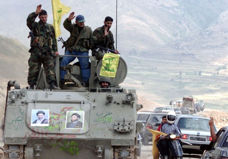 Pro-Iranian Hezbollah guerrillas, riding on an APC M113 used by pro-Israeli militiamen, wave to passing motorists as they drive in the former Israeli security zone in the Tell Nahas area of south Lebanon May 26, 2000. 