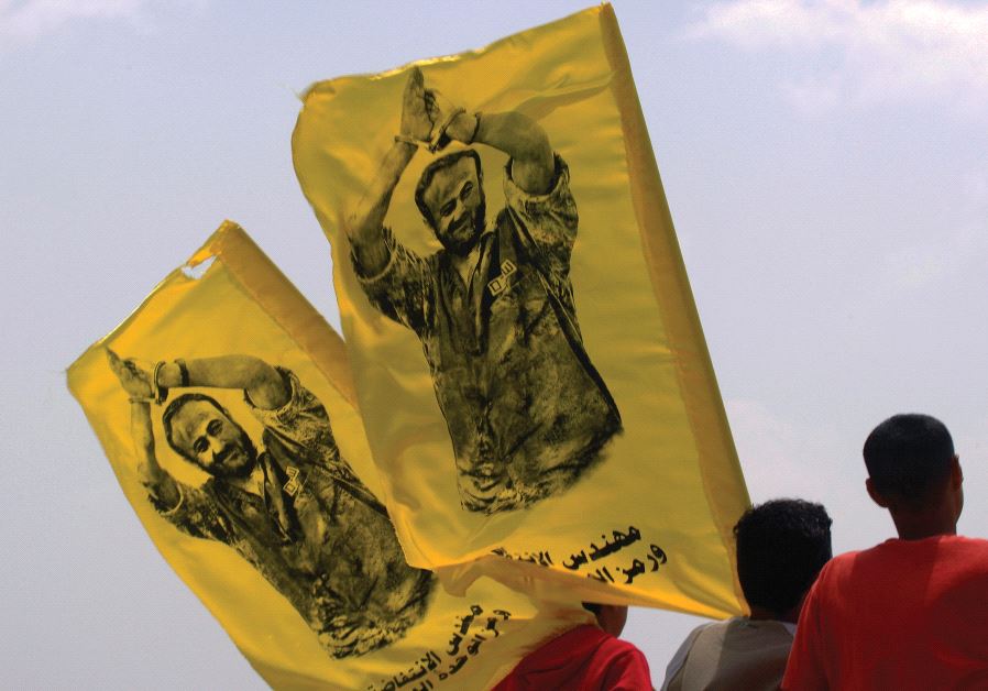 PALESTINIAN YOUTHS carry flags with the image of Marwan Barghouti during a protest in the West Bank