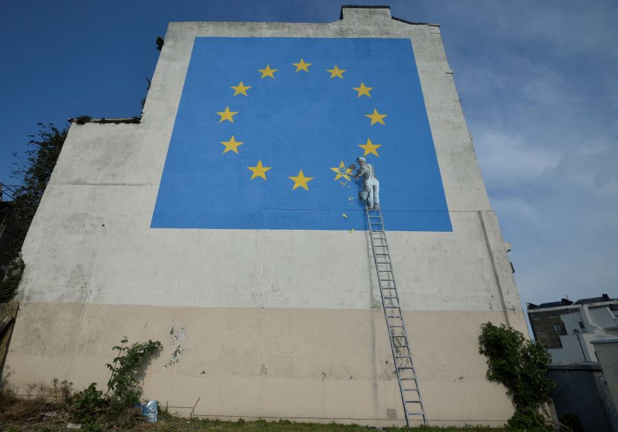 An artwork attributed to street artist Banksy, depicting a workman chipping away at one of the 12 stars on the flag of the European Union, is seen on a wall in the ferry port of Dover, Britain May 7, 2017