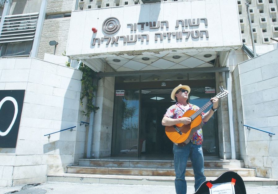 ARIEH O’SULLIVAN, ‘IBA English News’ anchor, plays the blues as the Israel Broadcasting Authority is shut down, in front of the IBA building in the capital’s Romema neighborhood