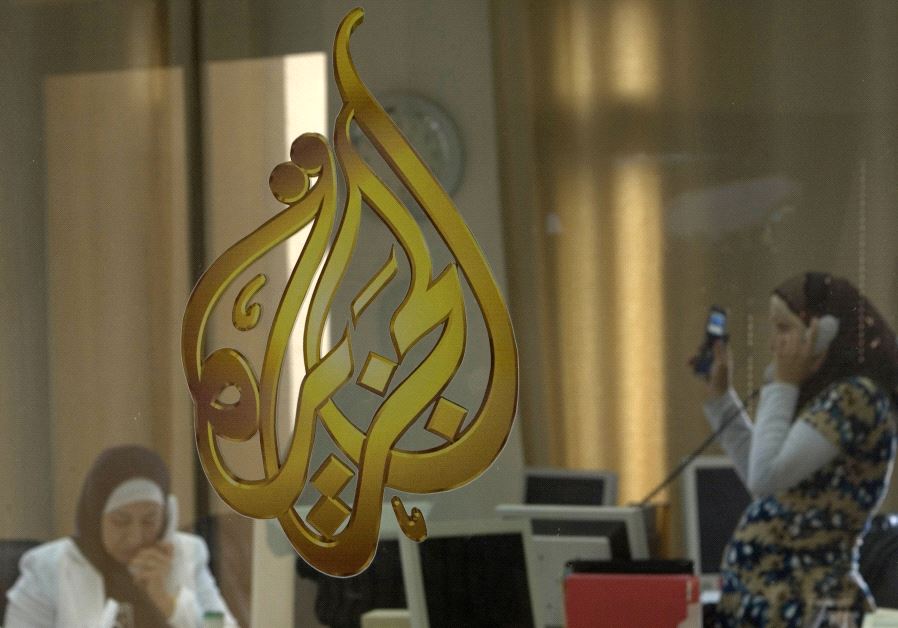 Palestinian journalists are seen through a glass window at the offices of the Arabic news channel Al-Jazeera in the West Bank city of Ramallah July 15, 2009.