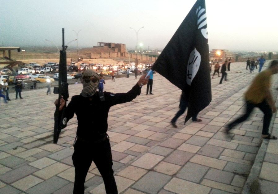 A fighter of the Islamic State of Iraq and the Levant (ISIL) holds an ISIL flag and a weapon on a street in the city of Mosul June 23, 2014.
